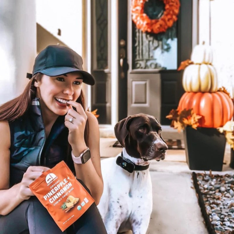 Woman Snacking Healthy Food With Autumn Flavors On Patio With Dog Organic Fruit Snack Mavuno Harvest Pineapple Cinnamon Fall Vibes